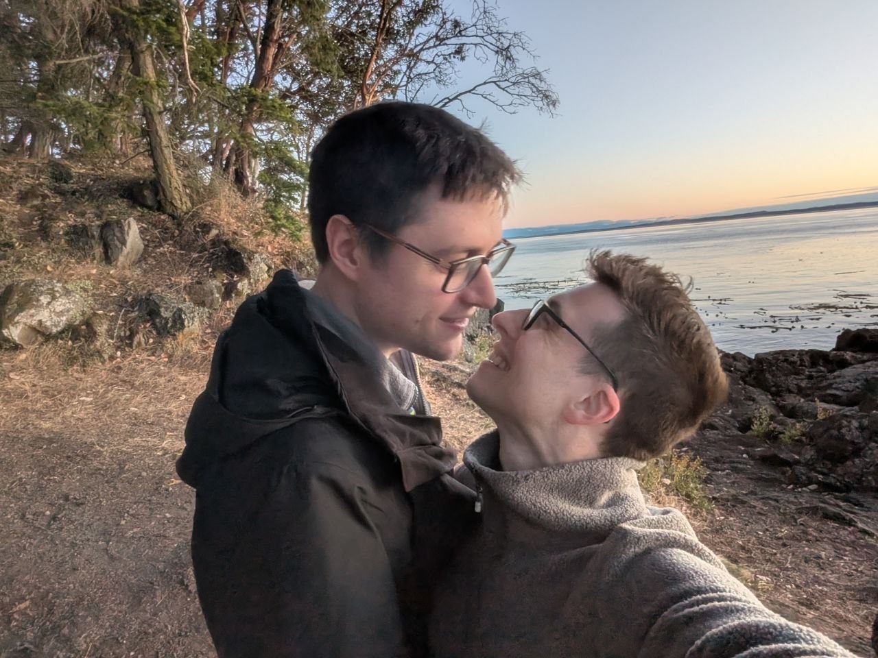 A kiss on a tree-lined shore at dusk